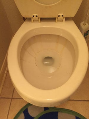 A dirty toilet bowl in a bathroom.