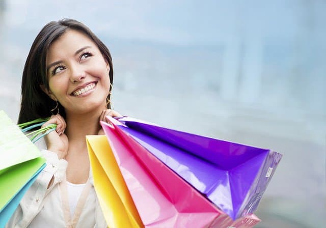 A woman holding shopping bags and smiling.