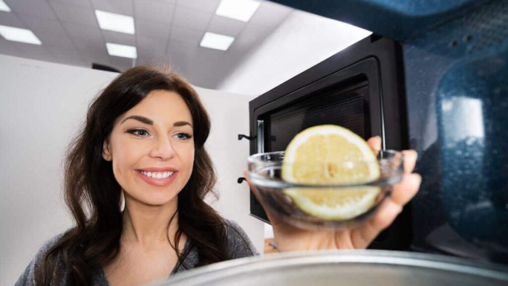 * Ways To Clean Your Microwave; Woman putting Lemon Water In Microwave
