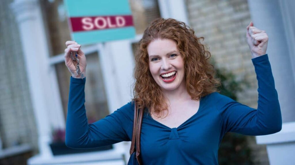 Buy a Home With No Money Down. Woman with Key and Sold Sign