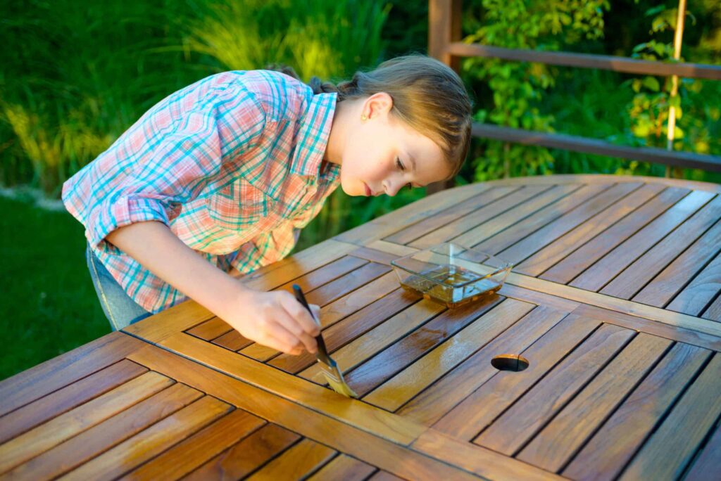 Best Tips for Cleaning Teak Furniture; Girl Treating Teak Furniture