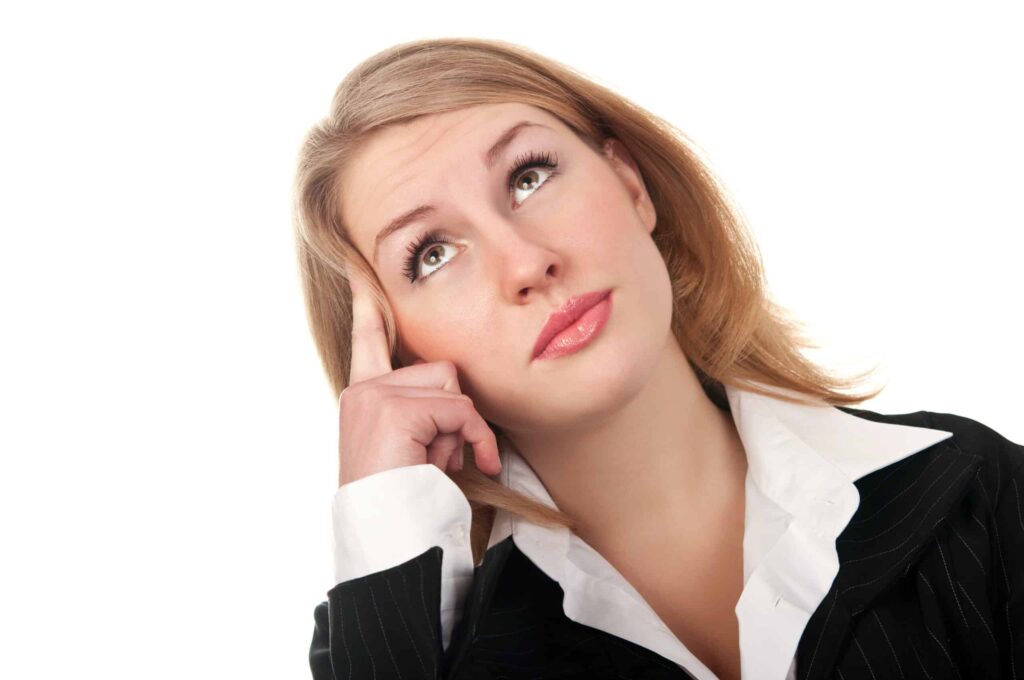 A person with light brown hair, wearing a black blazer and white shirt, is looking upwards with a thoughtful expression, resting their head on one hand against a white background, embodying the contemplative spirit of the working class.