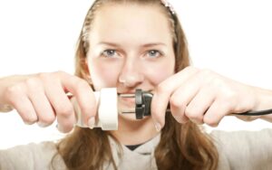 A person in a gray hoodie holds and connects a black plug to a white outlet adapter.