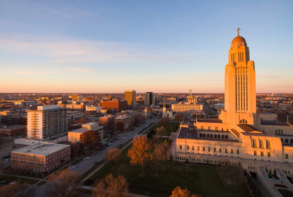 Aerial view of a cityscape at sunset with the prominent tall building, state capitol, surrounded by other structures and trees—often cited as one of the most comfortable places to live in the US.