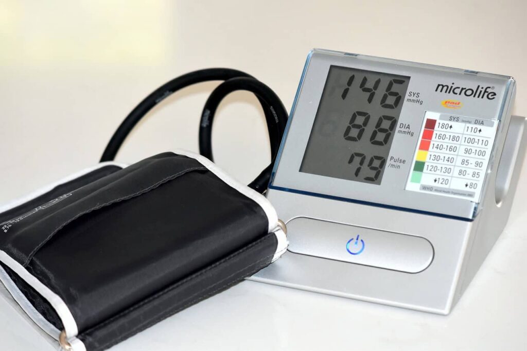 Digital blood pressure monitor displaying a reading of 146/88 with a pulse rate of 79. The cuff is attached and laid flat beside the device.