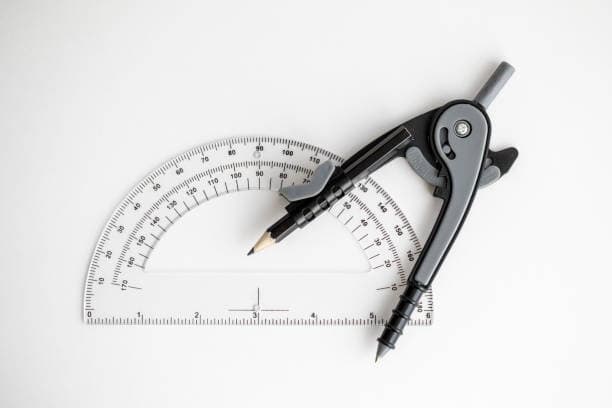 A clear plastic protractor and a metal and plastic drawing compass with a pencil are placed together on a white background.