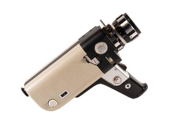 Vintage handheld film camera with a black and beige body, featuring a lens and various controls, isolated on a white background.