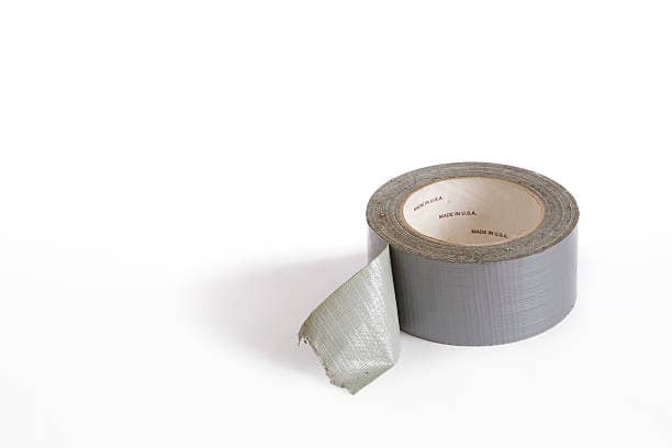 A partially unrolled roll of gray duct tape is positioned on a white surface.
