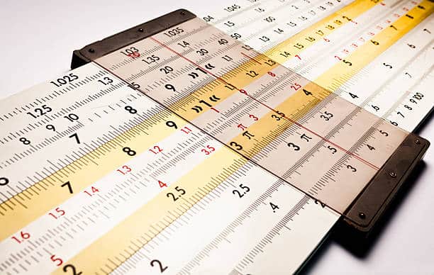 Close-up of a vintage slide rule with multiple scales and markings used for manual mathematical calculations.