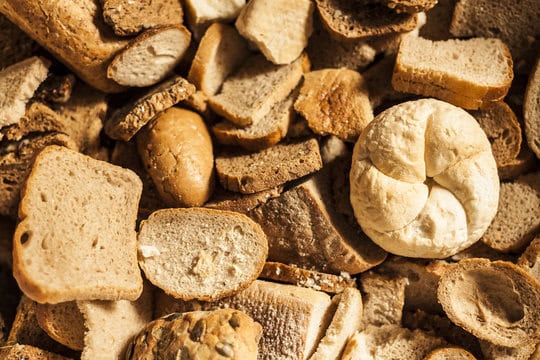 A close-up of an assortment of various types of sliced and whole bread pieces in different shapes and textures.