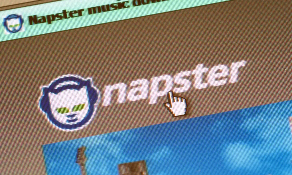 A computer screen displays the Napster logo and a hand cursor pointing to it, with "Napster music dow" visible in the top left corner.