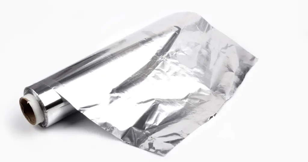 A partially unrolled roll of aluminum foil on a white background.