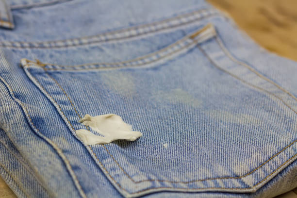 Chewing gum stuck on the front pocket of blue denim jeans.