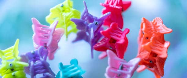 Close-up of colorful plastic butterfly hair clips arranged together against a blurred blue background.
