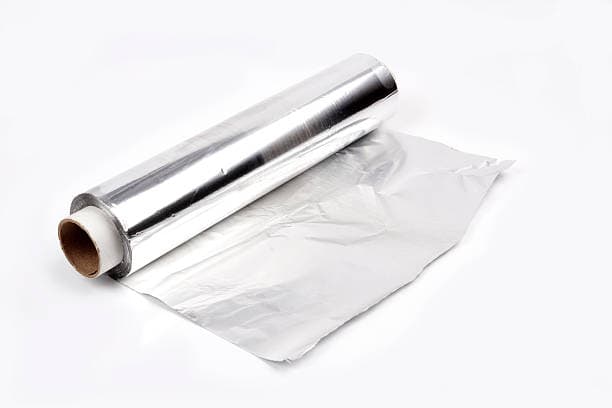 A partially unrolled roll of aluminum foil with a cardboard core on a white background.
