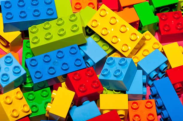 A pile of colorful interlocking plastic building blocks including blue, red, green, and yellow bricks.