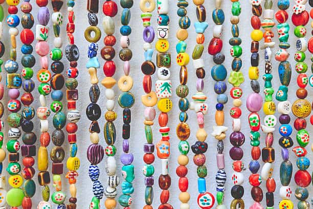 A variety of colorful ceramic beads of different shapes and sizes hanging on multiple strings.