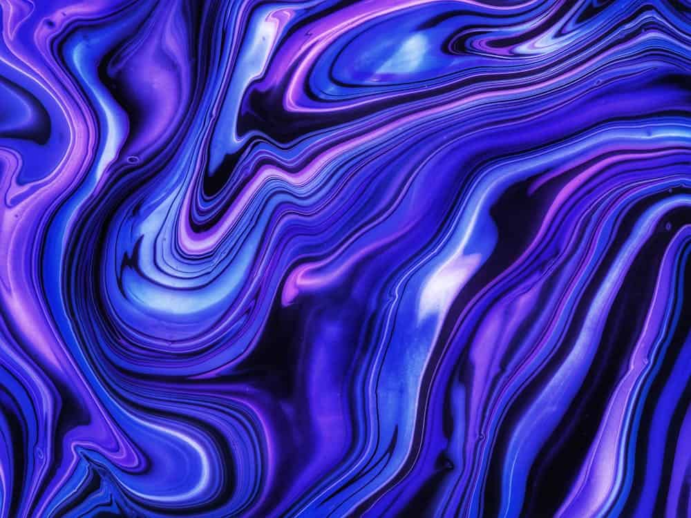 Abstract image featuring fluid, swirling patterns in various shades of violet, blue, and black. The colors blend seamlessly, creating a vibrant and dynamic visual effect.