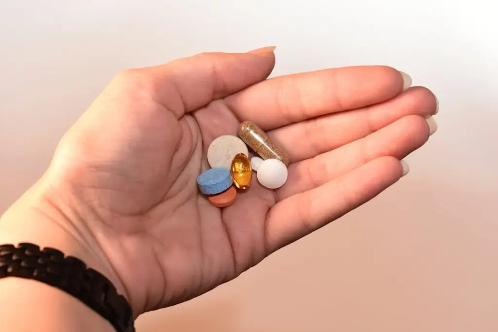 A hand holding various pills and capsules of different colors and sizes.