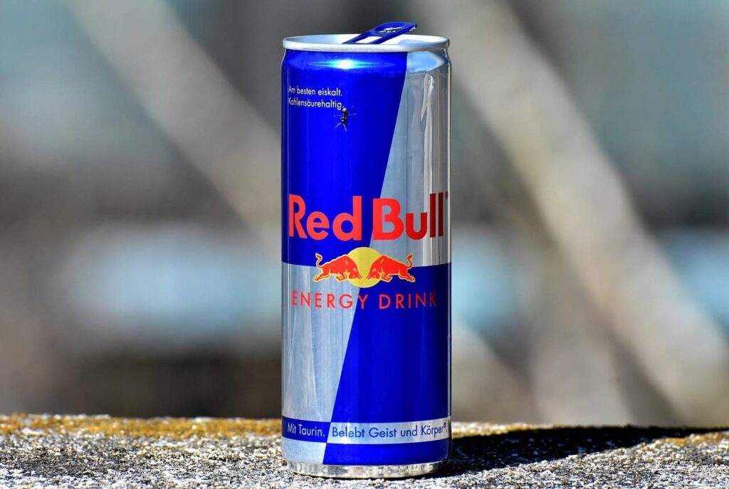 A can of Red Bull energy drink with its blue and silver design stands on a surface.