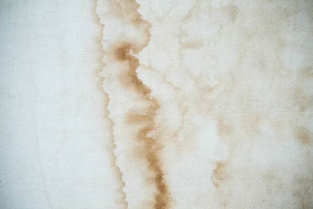 A patch of wall with visible brown water stains and discoloration.