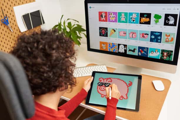 Person using a tablet to create a digital illustration of a pig while also viewing various animal illustrations on a computer screen.
