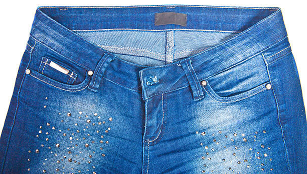 Close-up of blue denim jeans with studded embellishments around the pockets, showcasing the front view and waistband area.