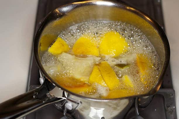 Lemon slices boiling in a pot of water on a stove.