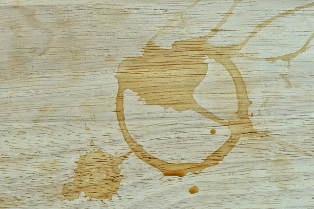A coffee cup ring stain and splash marks on a light wooden surface.