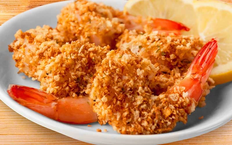 A plate of breaded and fried shrimp garnished with lemon slices.