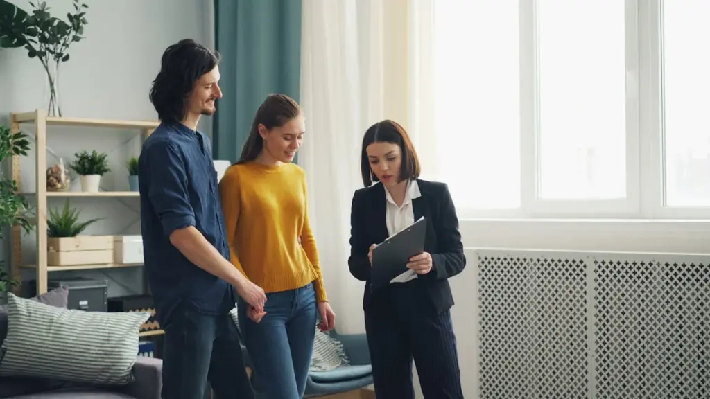 A businesswoman shows a clipboard to a man and woman in a living room. The room has a sofa, plants, and large windows.