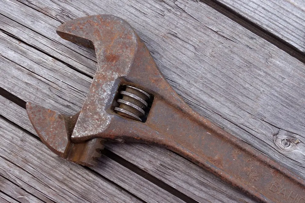 A rusty adjustable wrench on wooden boards.