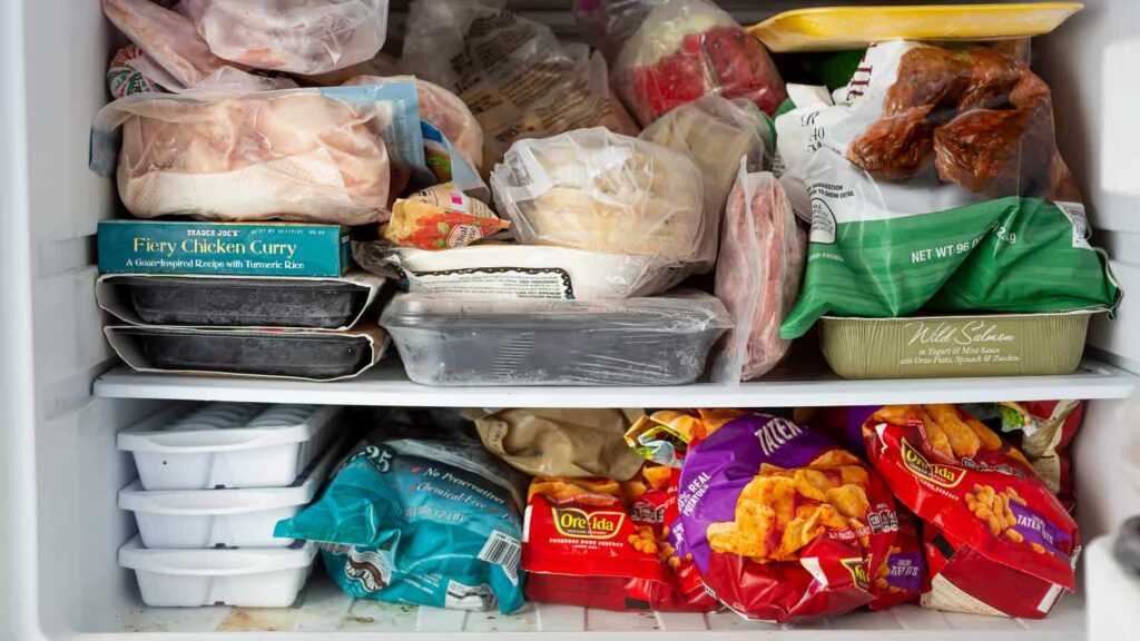 A freezer filled with various frozen foods, including packaged meats, dinners, and snack items.