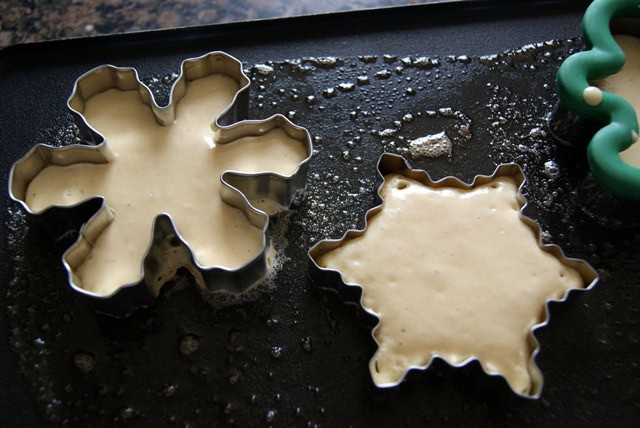 Two metallic star-shaped molds filled with batter on a baking tray.