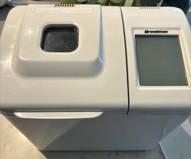 White Breadman bread maker with a viewing window and digital display, placed on a countertop.