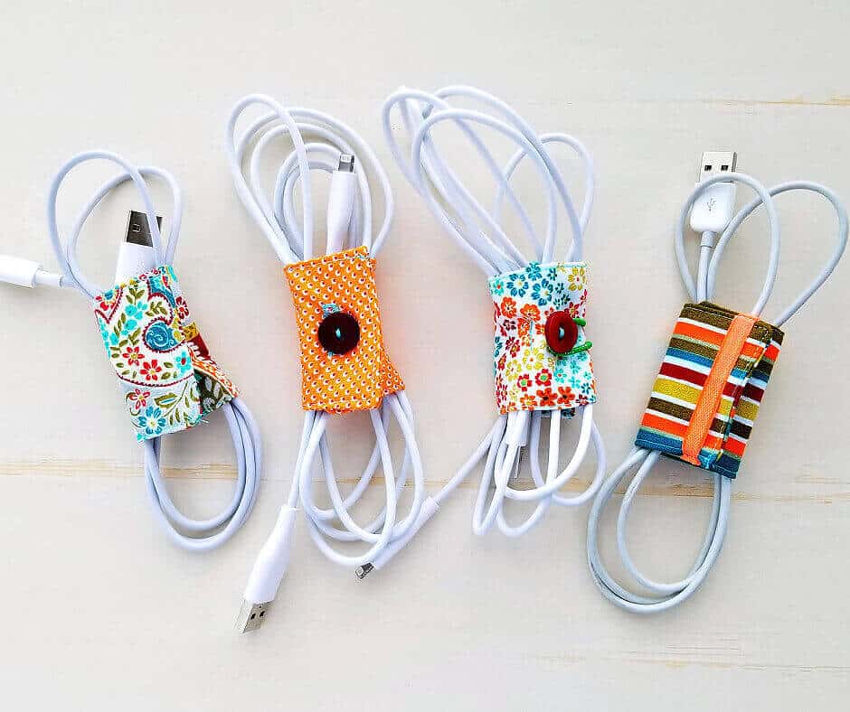 Four neatly coiled charging cables are secured with colorful, patterned fabric wraps featuring buttons.