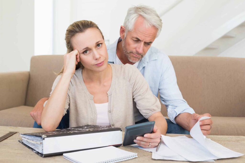 A couple reviewing financial documents and using a calculator at a table.