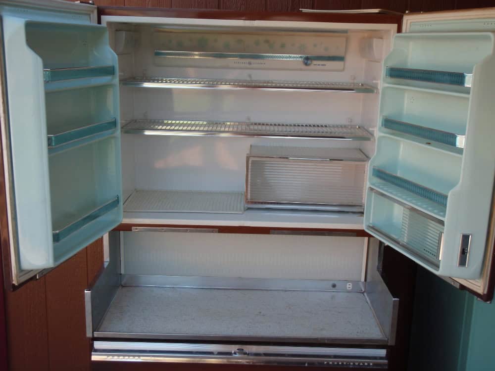 An open, empty refrigerator with double doors, multiple shelves, and door compartments.