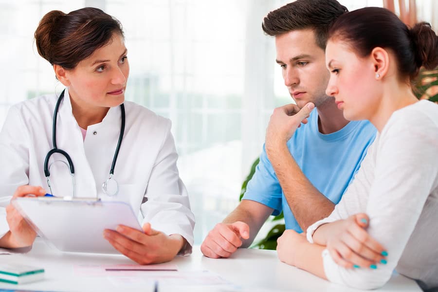 Doctor discussing medical results with a concerned couple in an office setting.