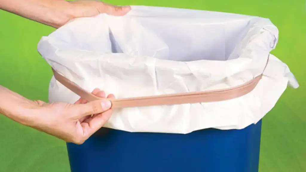 Hands securing a white trash bag with a rubber band to a blue trash can against a green background.