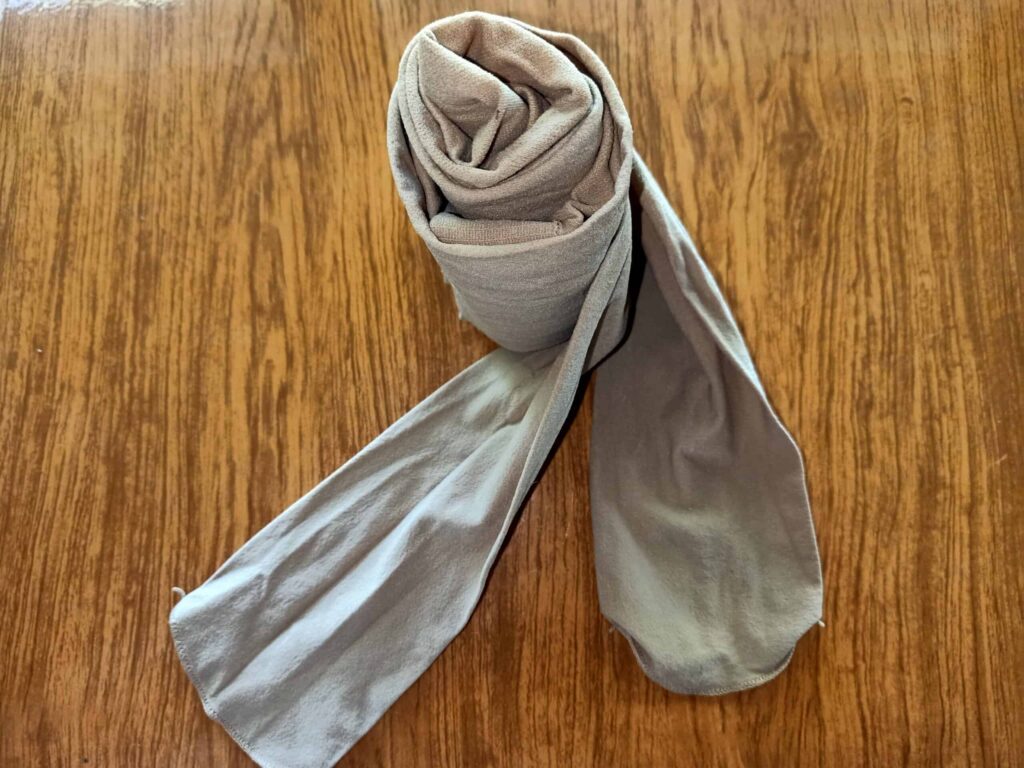 A neatly rolled pair of beige tights lies on a wooden surface.