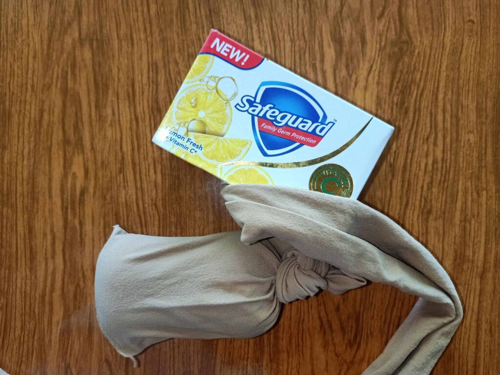 A box of Safeguard lemon fresh soap beside a knotted beige cloth on a wooden surface.