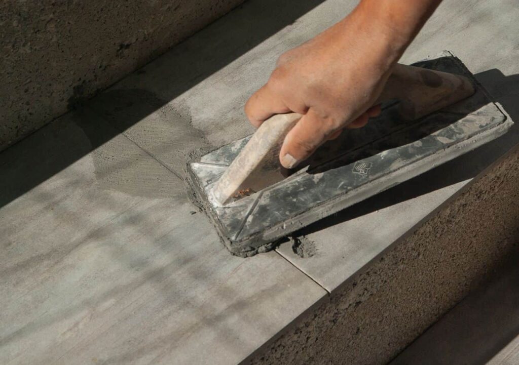 A hand using a float to smooth cement on a concrete surface.