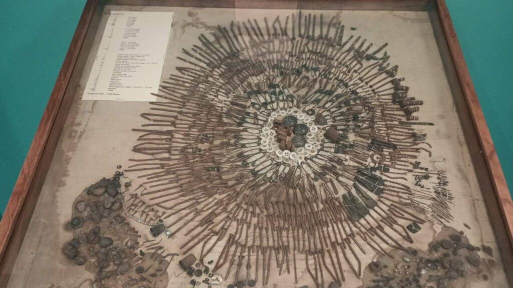 Display case with an intricate arrangement of various ancient tools and artifacts radiating from a central point. A list of items is visible in the upper left corner.