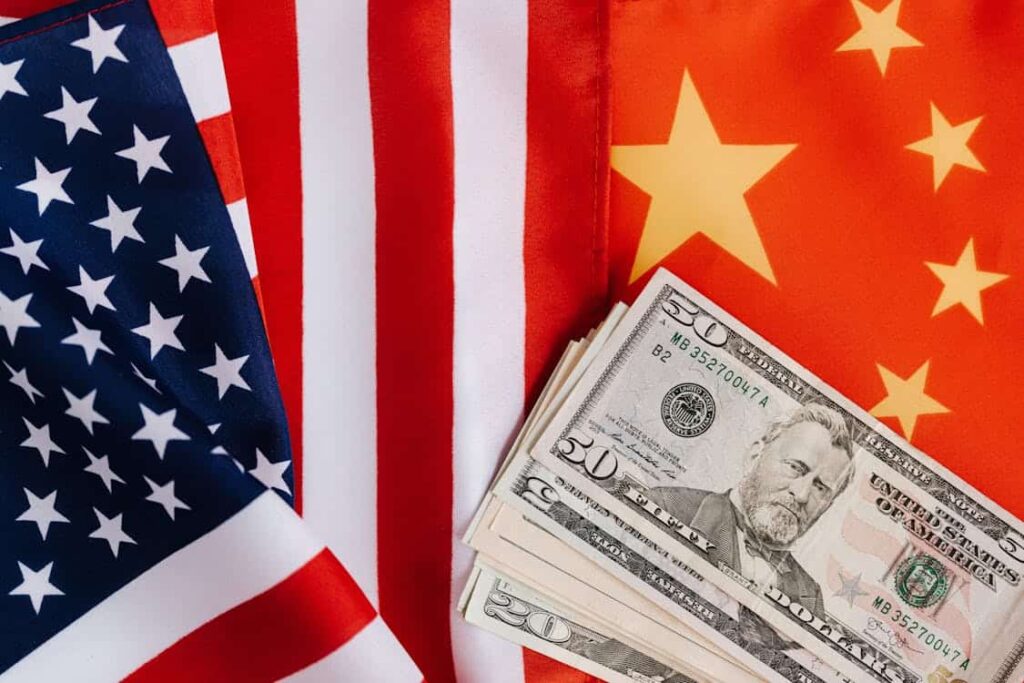 U.S. and Chinese flags with a stack of U.S. dollar bills in front.