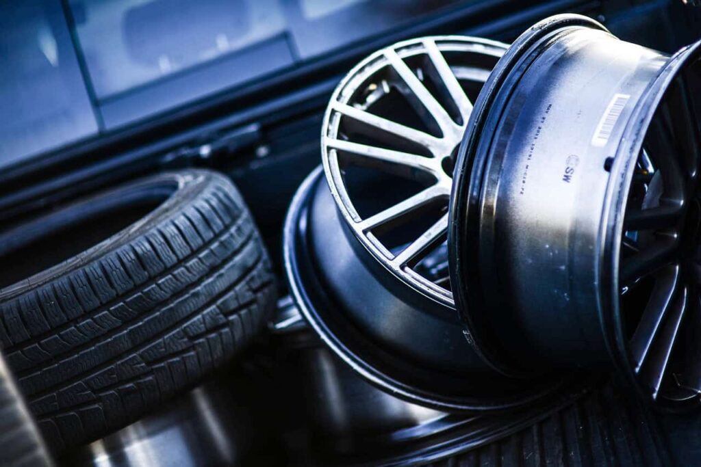 Car wheels and tires stacked in a vehicle trunk.