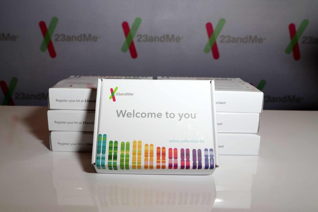 A stack of 23andMe saliva collection kits displayed on a table, with "Welcome to you" text prominently visible on the front kit.