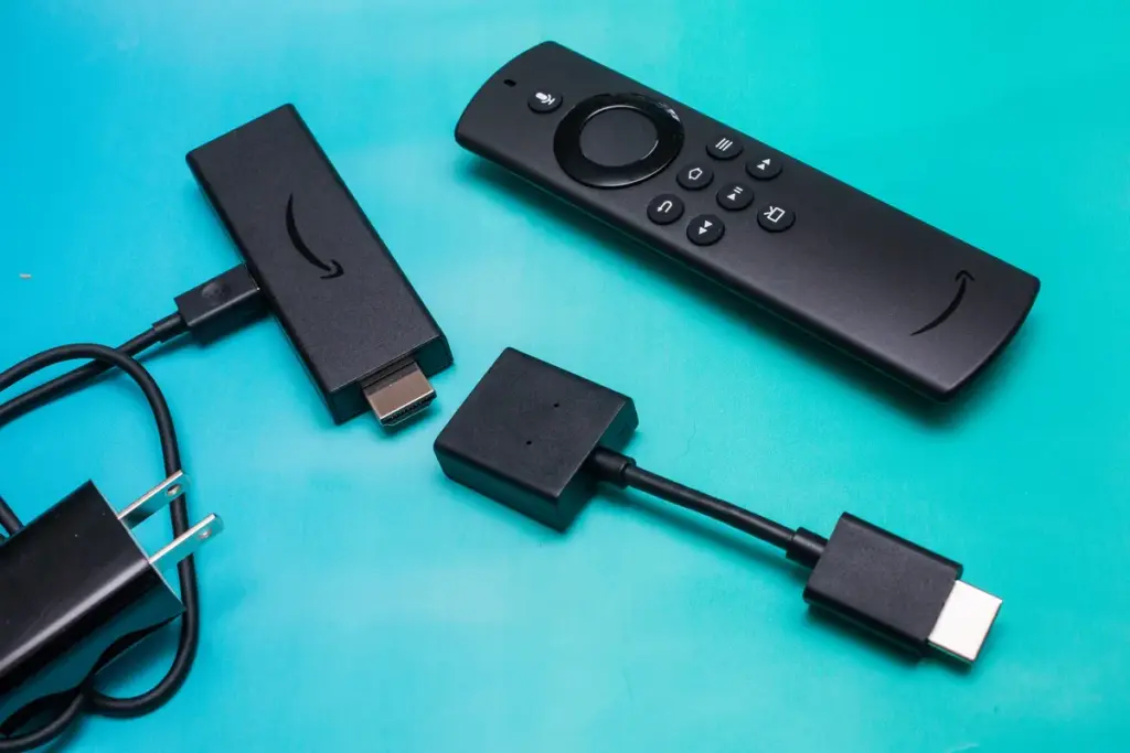 Streaming device kit on a teal background, including a remote control, HDMI stick, power adapter, and USB cable.
