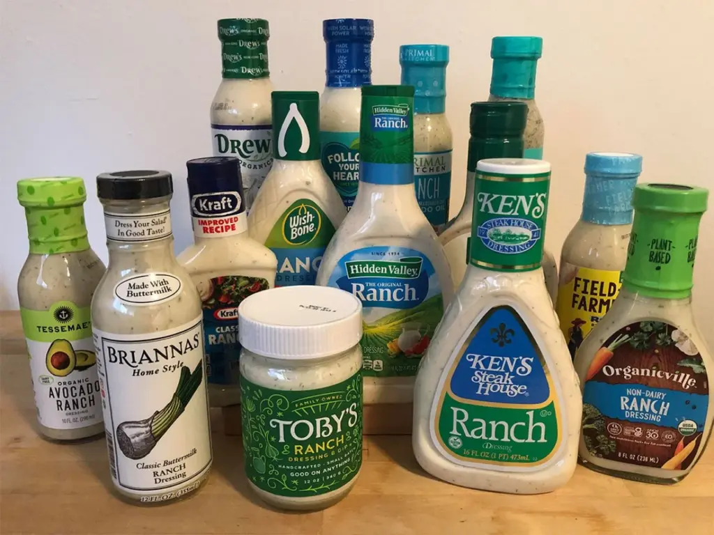 An assortment of various brands and types of ranch dressing bottles arranged on a surface.