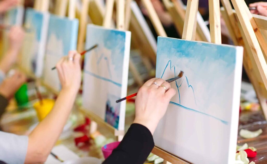 People painting landscapes on canvases at a class.